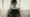 Silhouette d’une personne tenant une tablette derrière un rideau translucide.